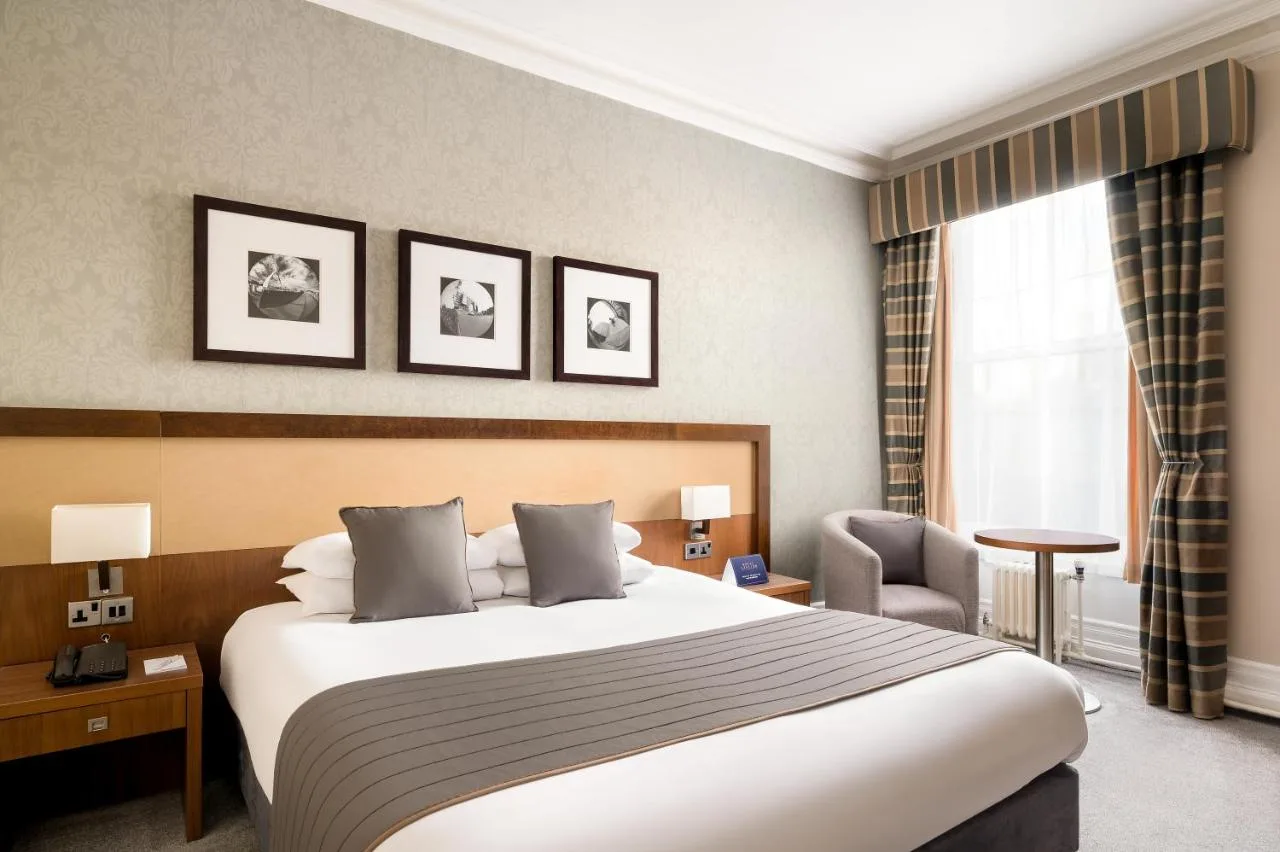 Hotel bedroom with a large bed and chair at Royal Station Hotel, Newcastle upon Tyne